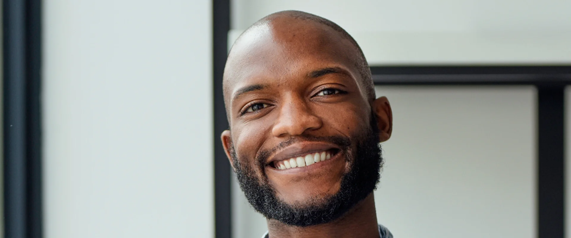 Smiling man with a beard indoors.