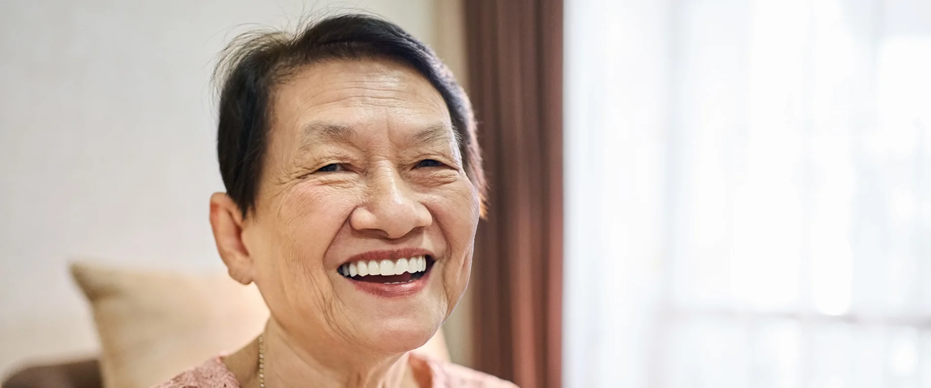 Smiling elderly woman in a cozy room.