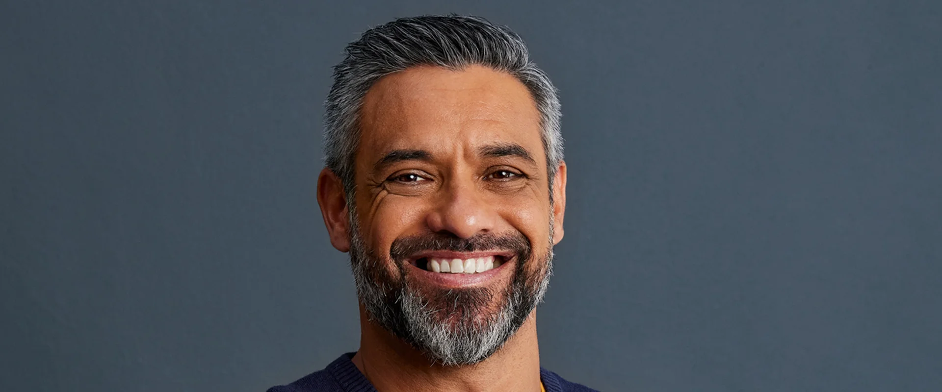 Smiling man with gray hair and beard.