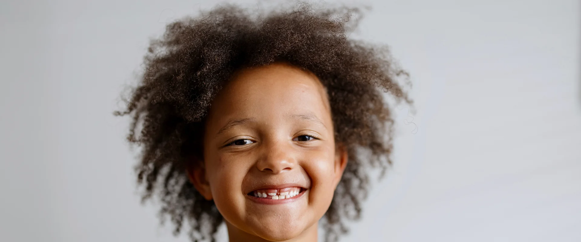Smiling child with curly hair, white background.
