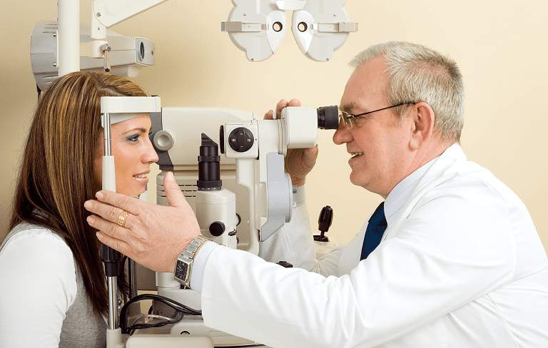 Eye doctor examining patient with slit lamp.