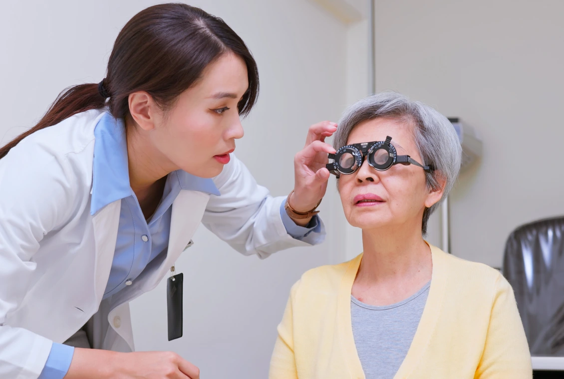 Optometrist examining elderly woman with phoropter.