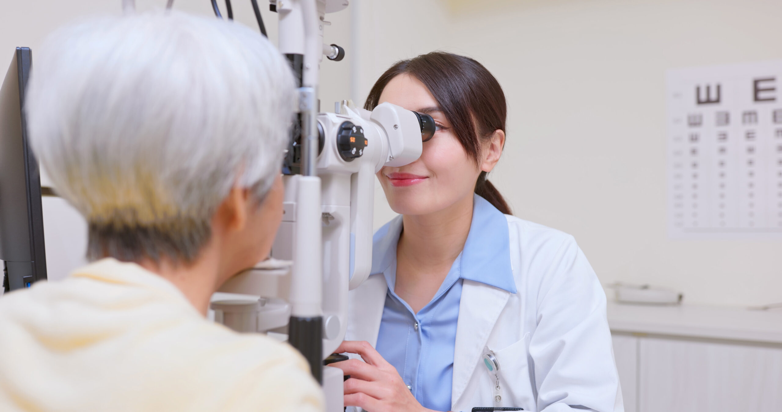 Optometrist examining a patient's eyes with a slit lamp.